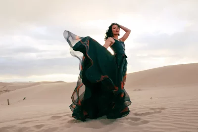 A model wears a flowing black dress in the desert.