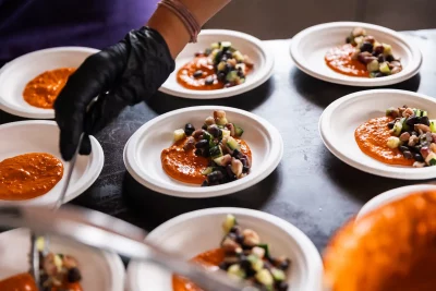 Plates of food are prepared for a course at the Three Sisters dinner