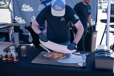 Dang Brother vendors slice up a fresh pizza at their booth at Farmers Market Ogden. 