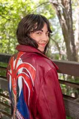 Blue Ruby owner Ammy Foste wears a red leather jacket. The back is painted with a humanoid creature shooting red vectors from its eyes.