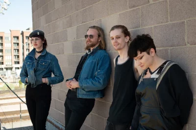 (L–R) Julie Boswell, Dirk Jeffrey, Connor Collings and Cecil Smith stand along a brick wall. Photo: Logan Sorenson