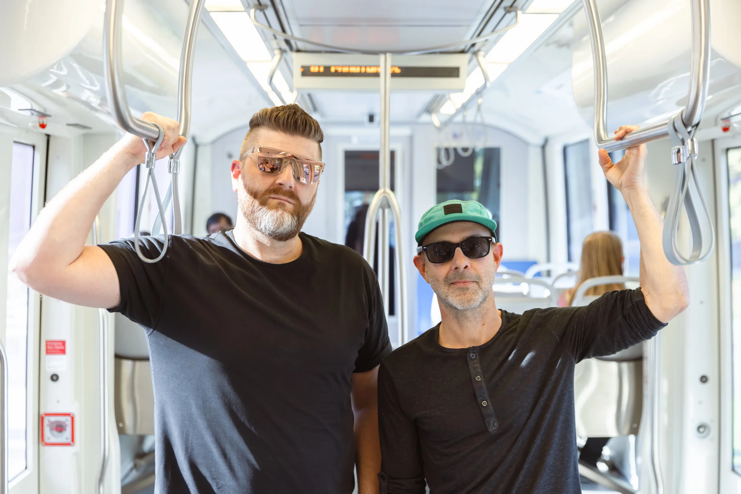 (L–R) Aaron Valentine and Mike Smith of local band Cassette Drift stand side-by-side as they ride the UTA Trax.