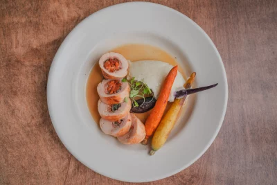 An entree at Caffé Molise. Two rainbow carrots, seafood, and microgreens line a neat white plate.