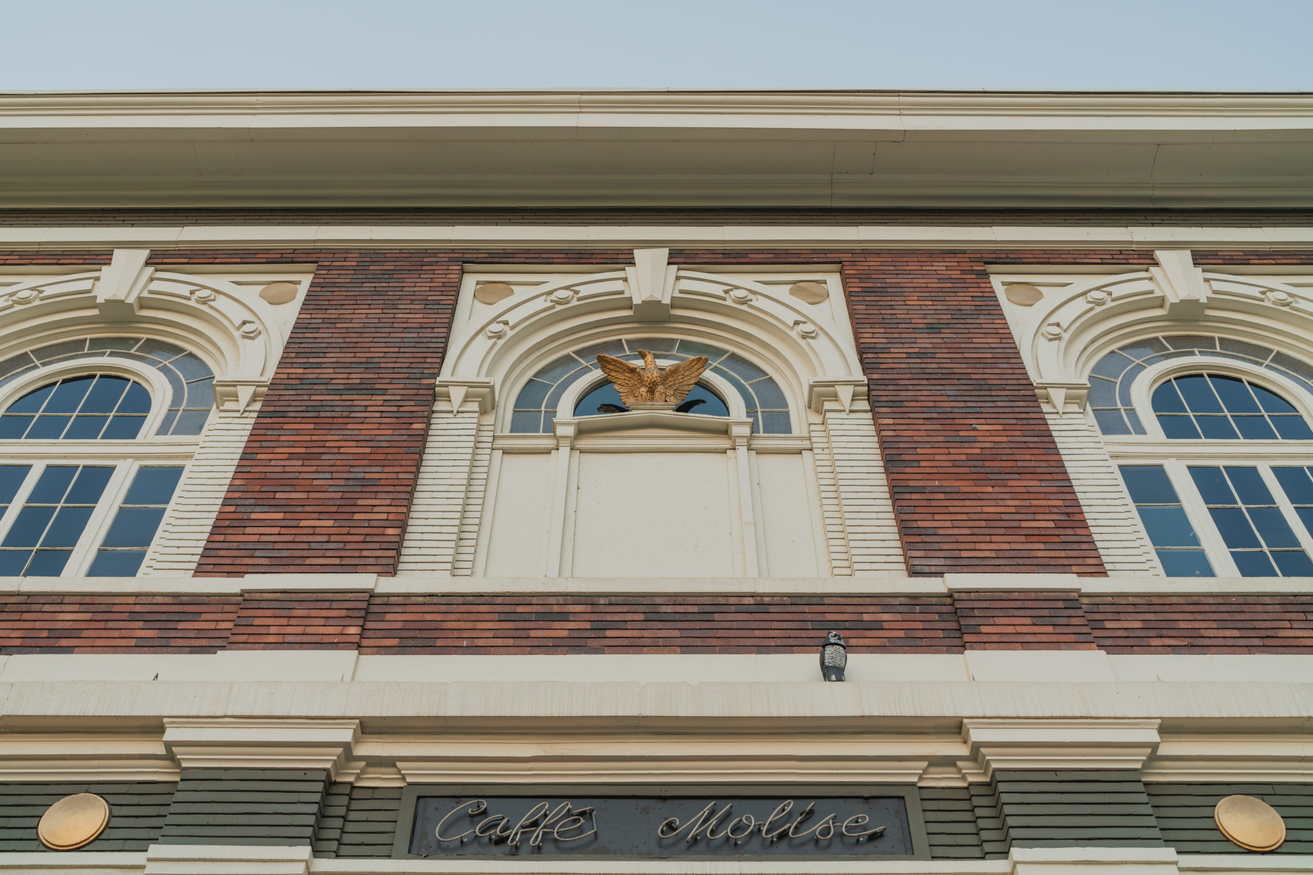 Exterior of Caffé Molise featuring a neon sign and a golden eagle statue.