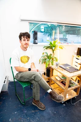 Reedy sits on a chair next to a plant and side table. 
