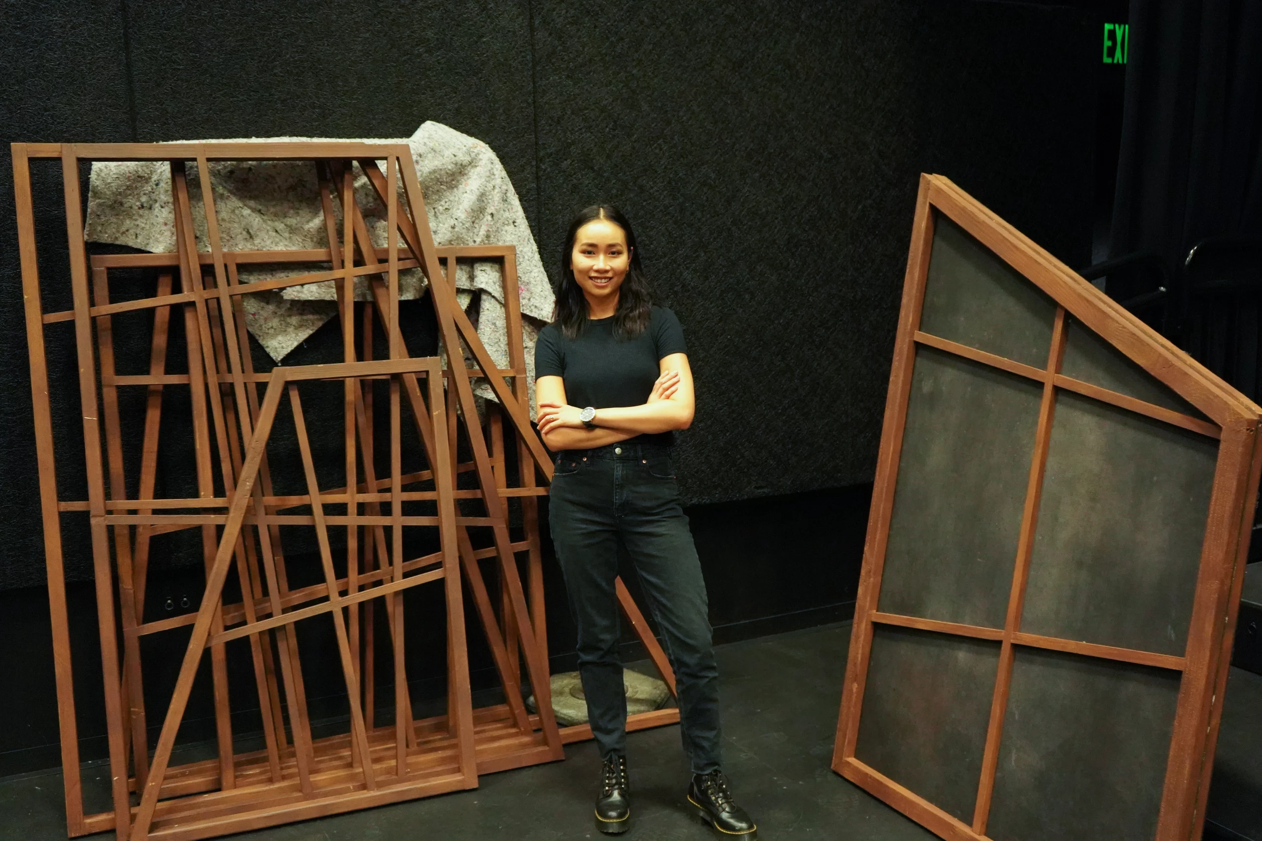 Janice Chan standing around pieces of theater backdrops.