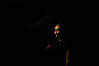 Janice Chan stands on a darkened set.