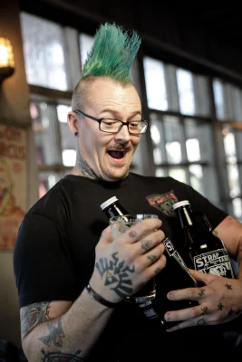 Derik DeBoard sports a blue mohawk and holds two growlers.