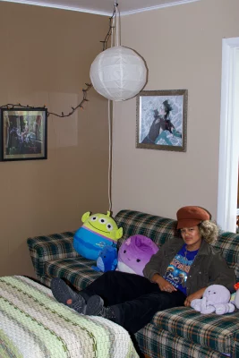 Katie, sitting on a plaid couch surrounded by stuffed animals.