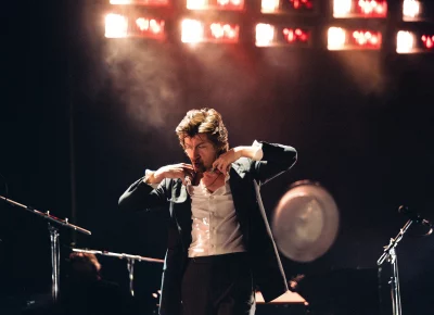 Lead singer for Arctic Monkeys Alex Turner adjusting his shirt collar.