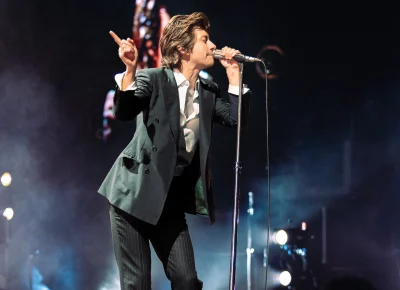 Arctic Monkey's Alex Turner leaning into his microphone.