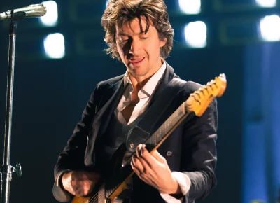 Alex Turner of Arctic Monkeys signing and playing guitar at the Delta Center.