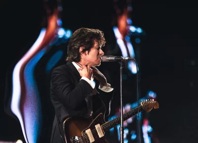 Alex Turner adjusting his collar while singing during the Arctic Monkey's Performance at the Delta Center.