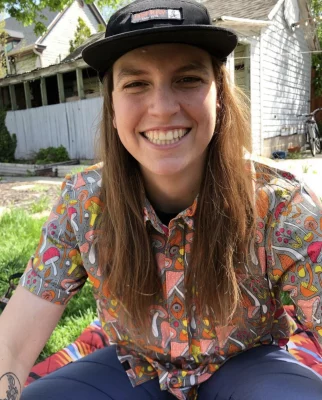 Owner and creator of Moon Gear, Jenna Battaglia, sits on a grassy lawn.