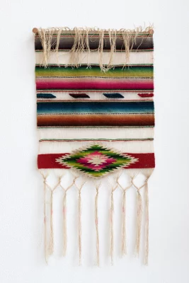 A striped blanket made by Kelly Tapìa-Chuning hanging on the wall.