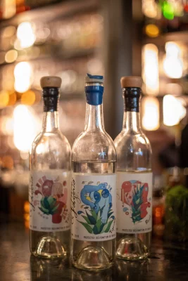 Three bottles of mezcal sit on the bar counter at Lake Effect. 