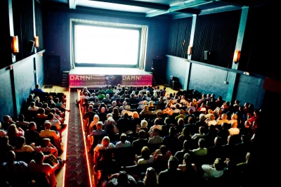 A crowd at the Tower Theater in Salt Lake watches a movie on a bright screen. 