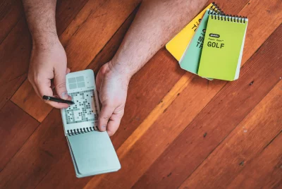 A photo of Tom Brinton writing in an Paper Apps DUNGEON notebook. Sitting to the side are the other products in the Paper Apps series. Photo: Ashley Christenson 