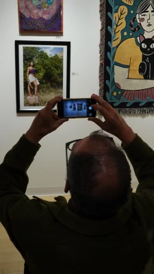 A gallery attendee taking a picture with their phone of the art on display.