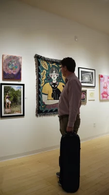 A gallery attendee viewing a wall of framed artwork.