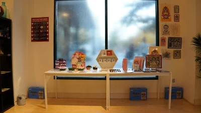 A shot of a table with art for sale in front of a frosted window.