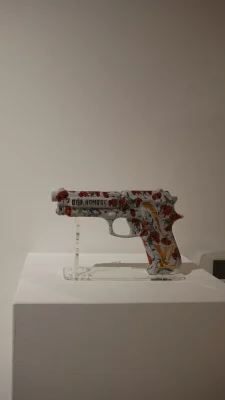 A sculpture of a gun, covered in stickers.