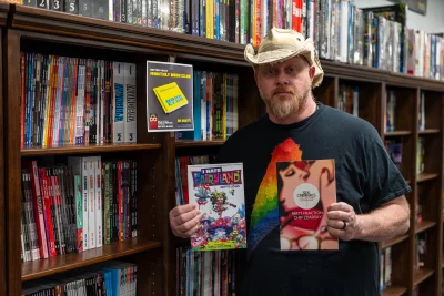 Dr. Volt's Manager Jeff Bell holds up two comics in the shop.