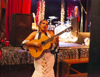 Rovie Wade performing their drag set which incorporated hispanic culture. They are seen with a classical guitar. Photo: Abel Cayas