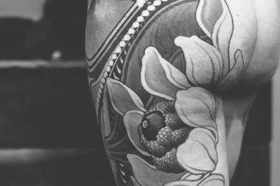 A detailed flower tattoo going up the back of a woman's thigh.