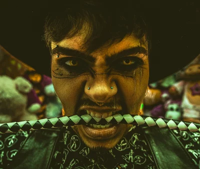 Heller Highwater bares his teeth with a bolo tie string in his mouth.