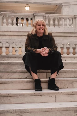 UFC Director Virginia Pearce sits smiling on a staircase.