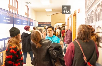 A Market volunteer stands among a crowd of shoppers.