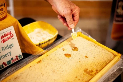 Honey is scraped off the honeycomb at the Holiday Market.