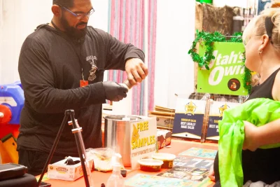 A vendor pours a free sample of salsa for a customer at Sauced up Salsa.