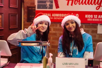 Two Craft Lake City volunteers wearing Santa hats at the entry booth.