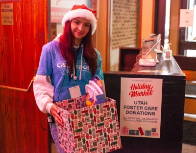 A Craft Lake City volunteer holding a gift-wrapped donation box for Utah Foster Care.