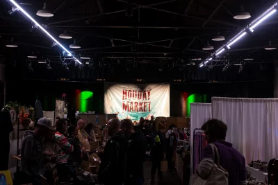 The crowd at the Holiday Market with a banner in the background.