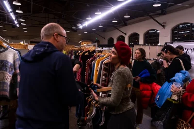Two people discuss vintage clothing amid the racks.