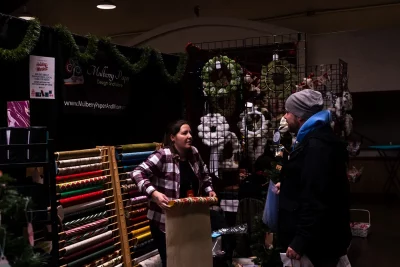A vendor at Mulberry Paper and More unrolls festive wrapping paper.