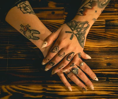 A close-up shot of Kat Aleman's hands, showing her rings, pointy nails and finger tattoos.