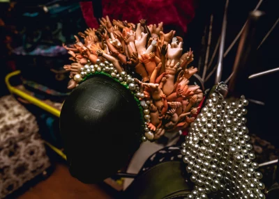 A crown made of pearls and plastic baby doll hands on a mannequin head. 