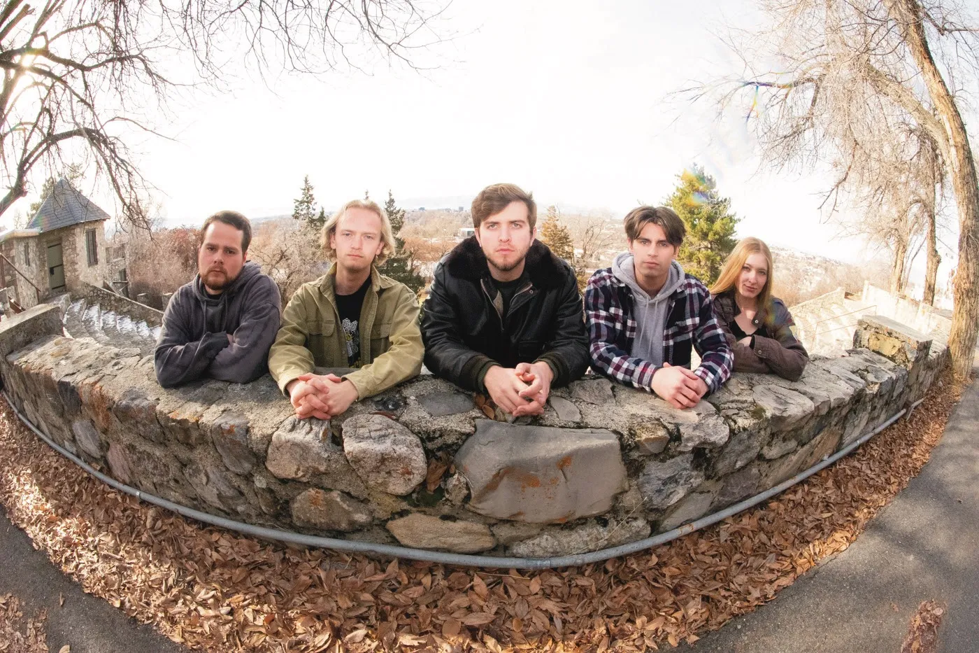 The members of No Such Animal lean on a cobblestone wall through a fisheye lens.