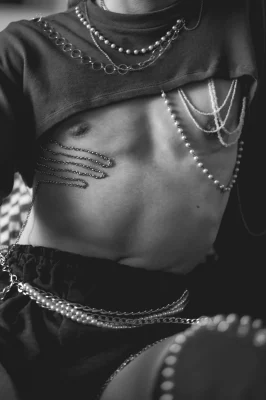 A black and white photo of pearls and chains on Robin D'Banc's chest and waist.