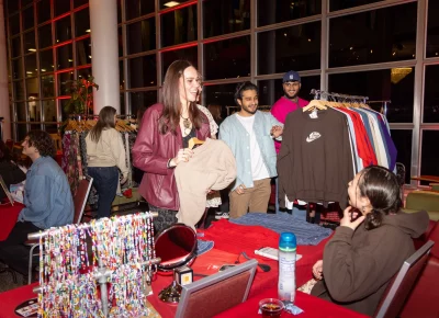 Gaby Hale (seated) sells a sweater during intermission at the 2nd Annual Fashion in Business runway show. Photo: John Barkiple