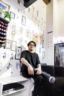Bryan Vigil sits in front of a wall where his watercolor paints are hung. 