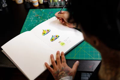 Bryan Vigil sketches potential tattoos in a notebook. 