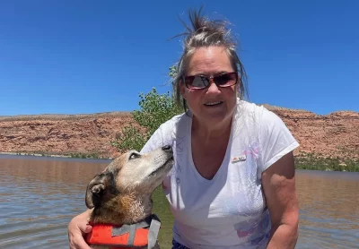 Katy Gullete smiles into the camera with a dog glancing up at her. 