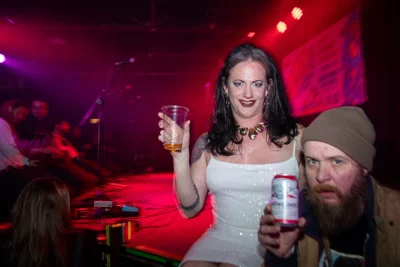 Sofia Scott smiles while holding up a plastic cup next to Mike Brown, holding a Budweiser can.