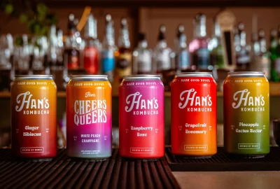 A colorful display of the different Han's Kombucha cans across a bartop.
