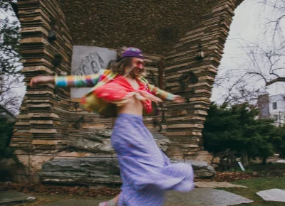 Bly Wallentine applyss lipstick while wearing a colorful outfit.